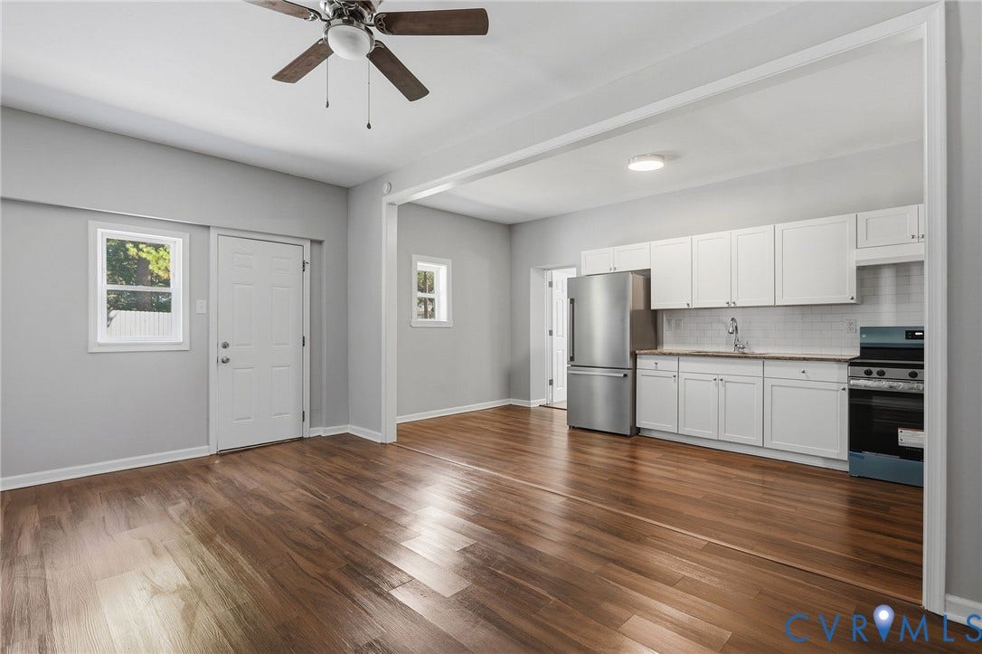 Wood-finish flooring throughout, white shaker-style cabinetry, stainless steel refrigerator, and a ceiling fan