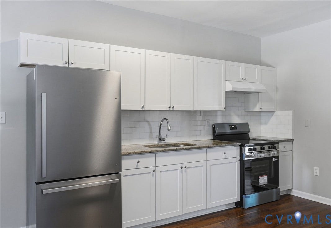 Kitchen featuring stainless steel appliances, white shaker-style cabinetry, a subway tile backsplash, granite countertops, and wood-finish flooring