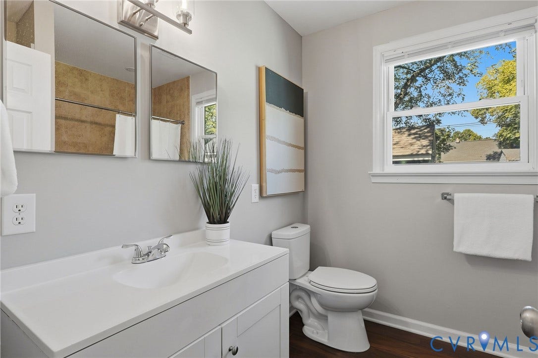 White vanity with integrated sink, dual mirrors, and contemporary lighting fixture