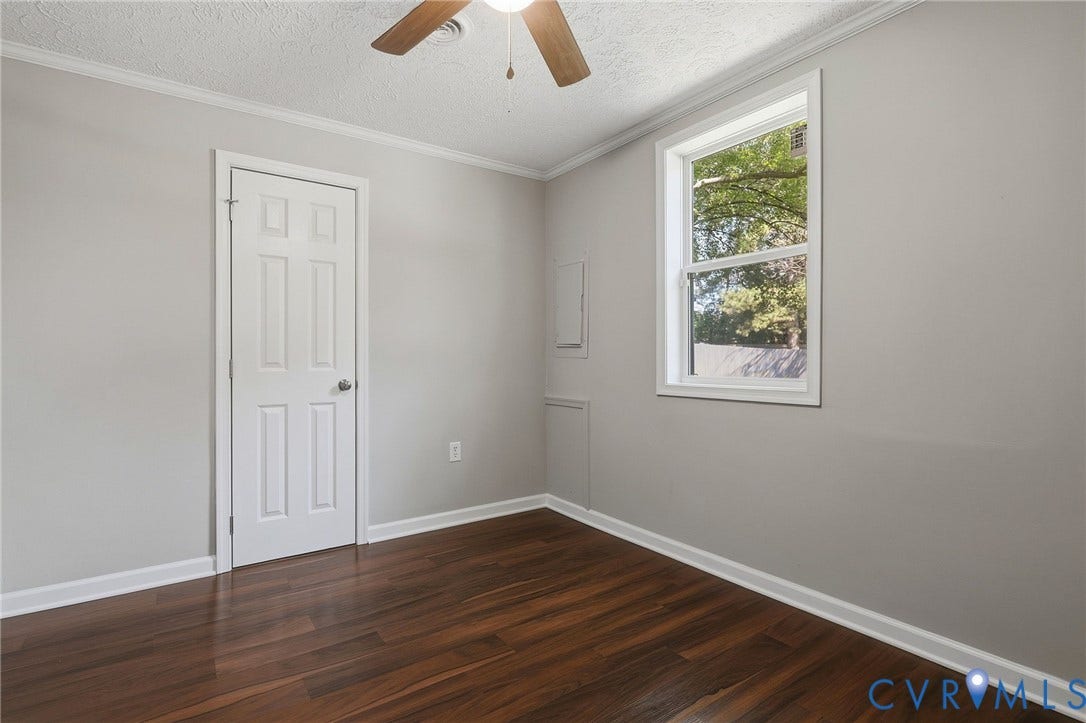 Wood-finish flooring, white trim, and a ceiling fan with light fixture