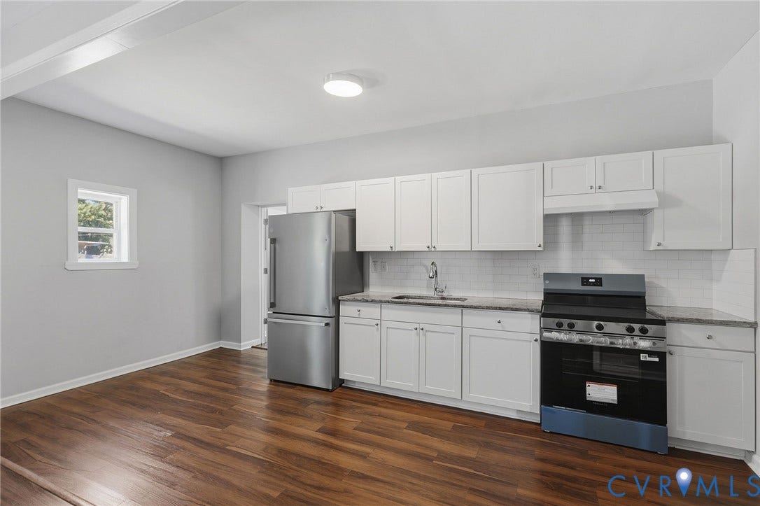 Modern kitchen featuring white cabinetry, a subway tile backsplash, stainless steel appliances, and wood-finish flooring