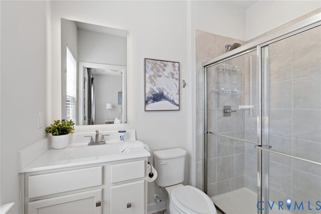 Tall vanity with a single basin sink, brushed nickel faucet, oversized tile in the walk in shower and dual showerheads