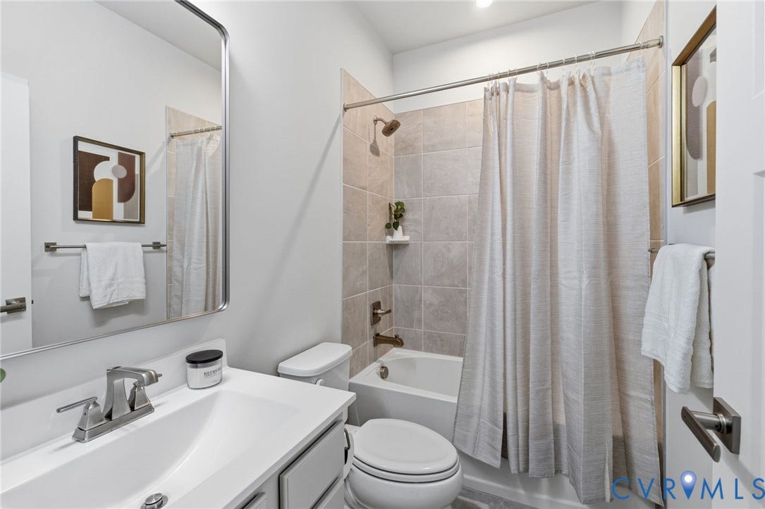 White vanity with chrome faucet, bathtub with oversized tile