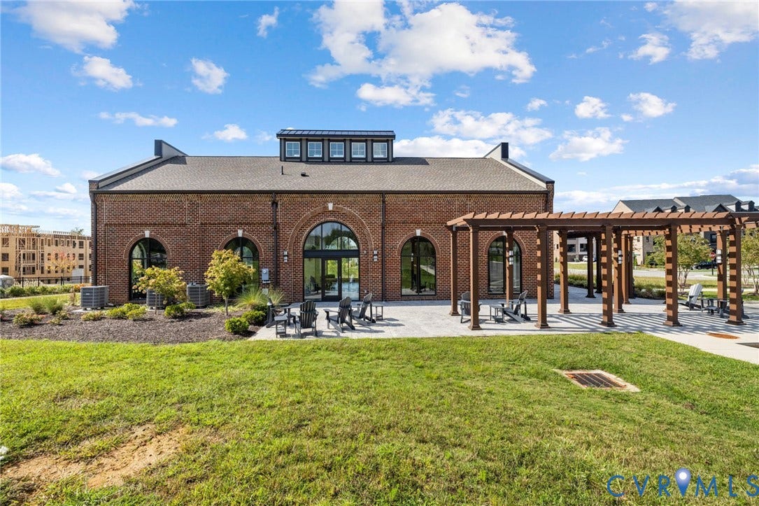 Brick exterior with arched window openings, a prominent pergola, and a large lawn area