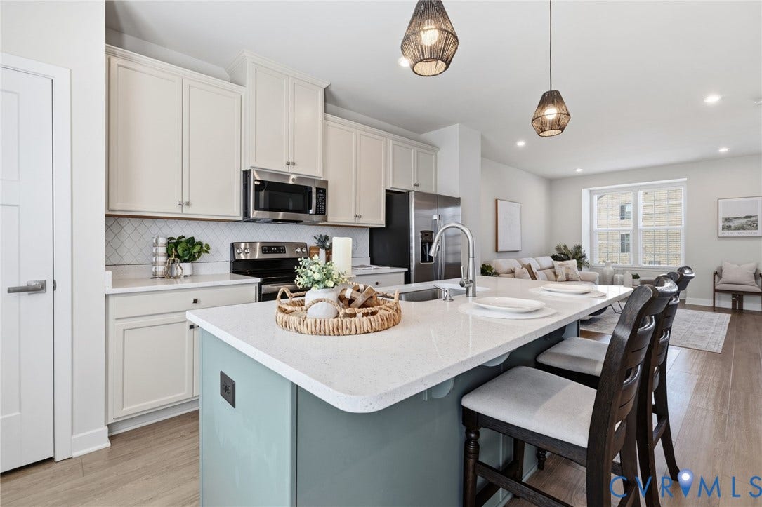 Kitchen featuring a central island with quartz countertop, stainless steel appliances, a  custom tile backsplash, light-toned cabinetry, and recessed lighting