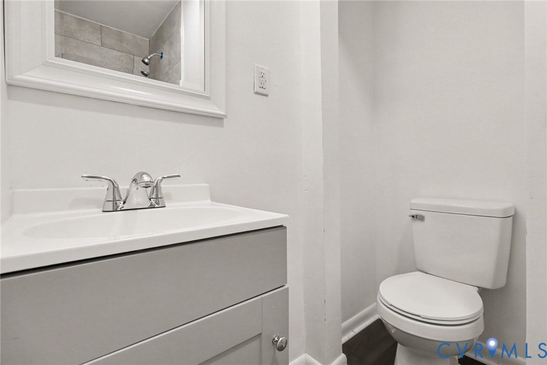 Vanity with integrated sink and chrome fixtures, framed mirror, and commode