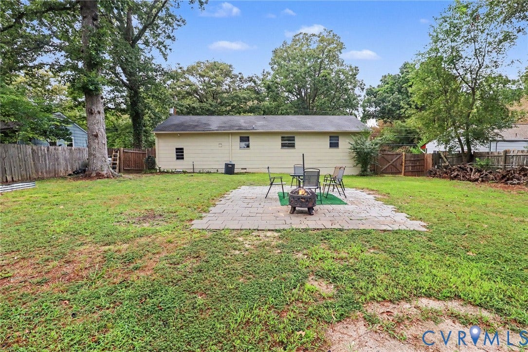 Expansive backyard featuring a paver patio, wood fencing, and mature trees