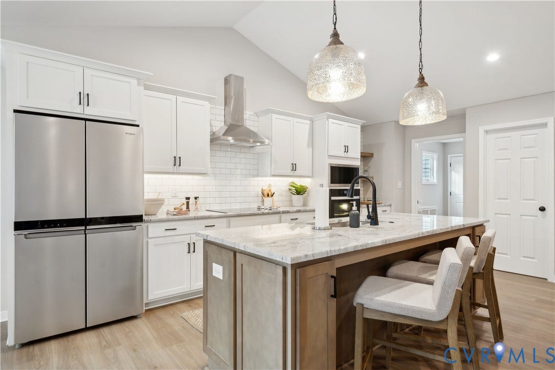 535 Wendenburg Terrace, #MODEL, Kennington, Aylett, VA 23009 Kitchen featuring stainless steel appliances, white cabinetry, light wood-finish flooring, a center island with countertop seating, and vaulted ceilings