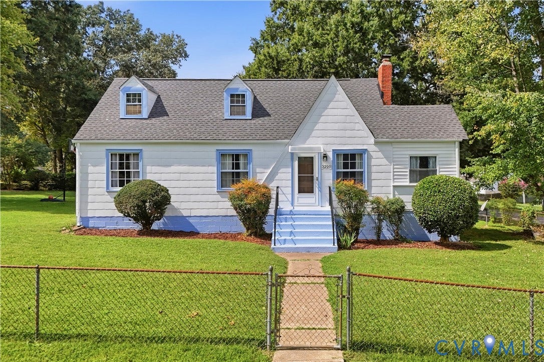White siding exterior with a dark shingle roof and three dormer windows