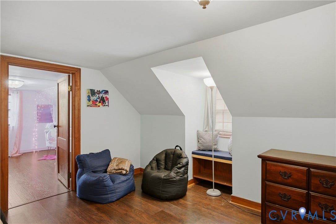 Sloped ceiling featuring wood-finish flooring, a built-in window bench, and an interior wood-frame door