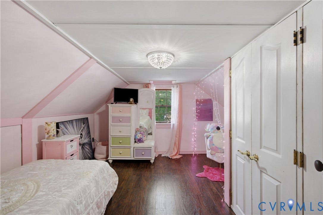 Sloped ceiling architecture with recessed storage, wood-finish flooring, and a crystal chandelier