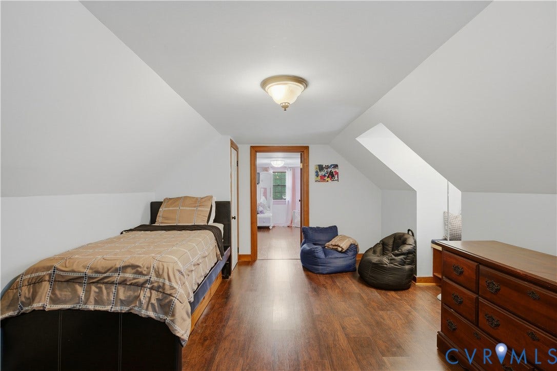 Wood-finish flooring with sloped ceilings and a flush-mount light fixture