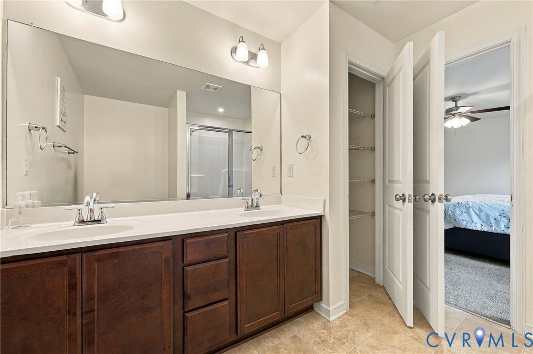 Spacious primary bath with double vanity, oversized mirror, and additional linen storage.