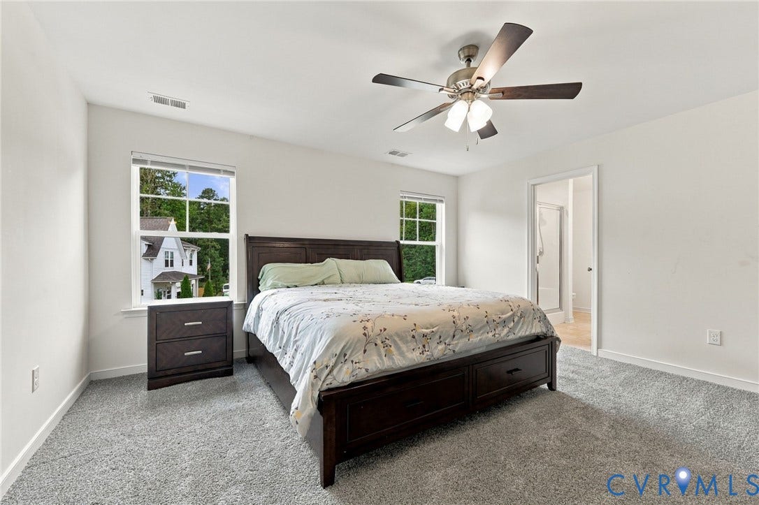 Generously sized primary bedroom with multiple windows, ceiling fan, brand new carpet and private en-suite bath.
