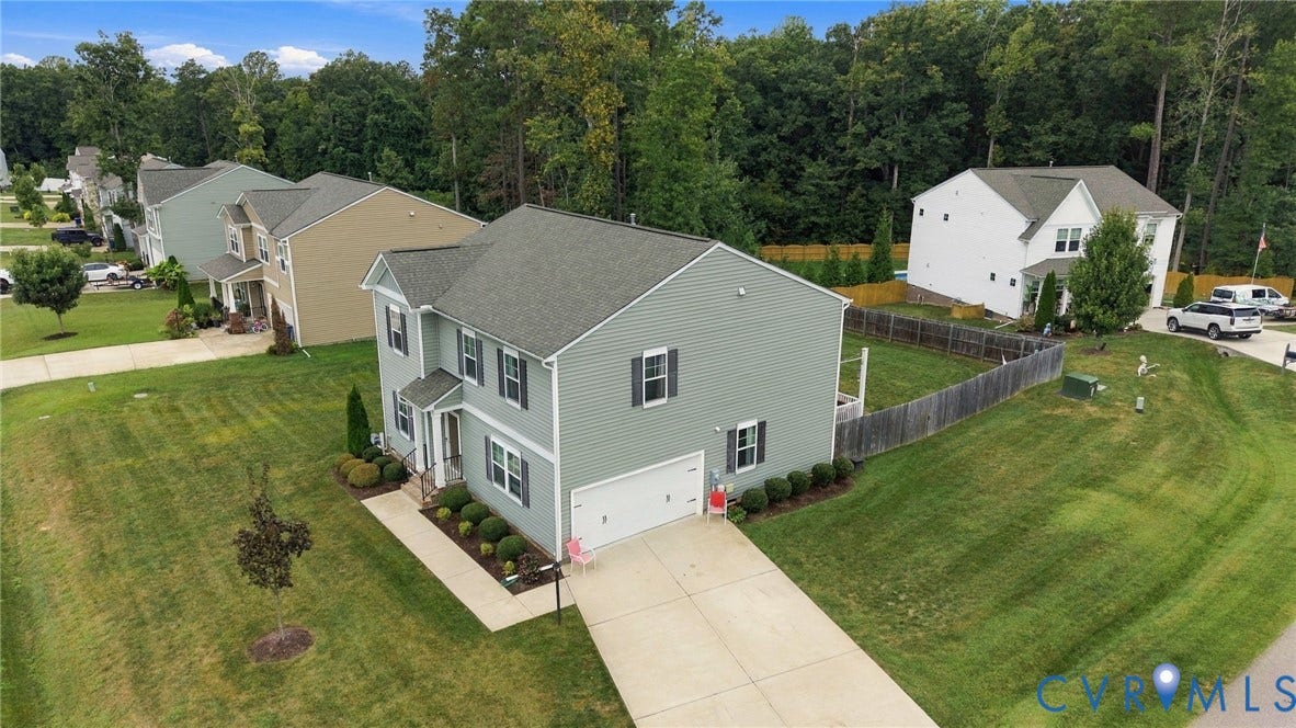 Aerial view showcases the home, attached two-car garage, landscaped exterior, and spacious homesite.