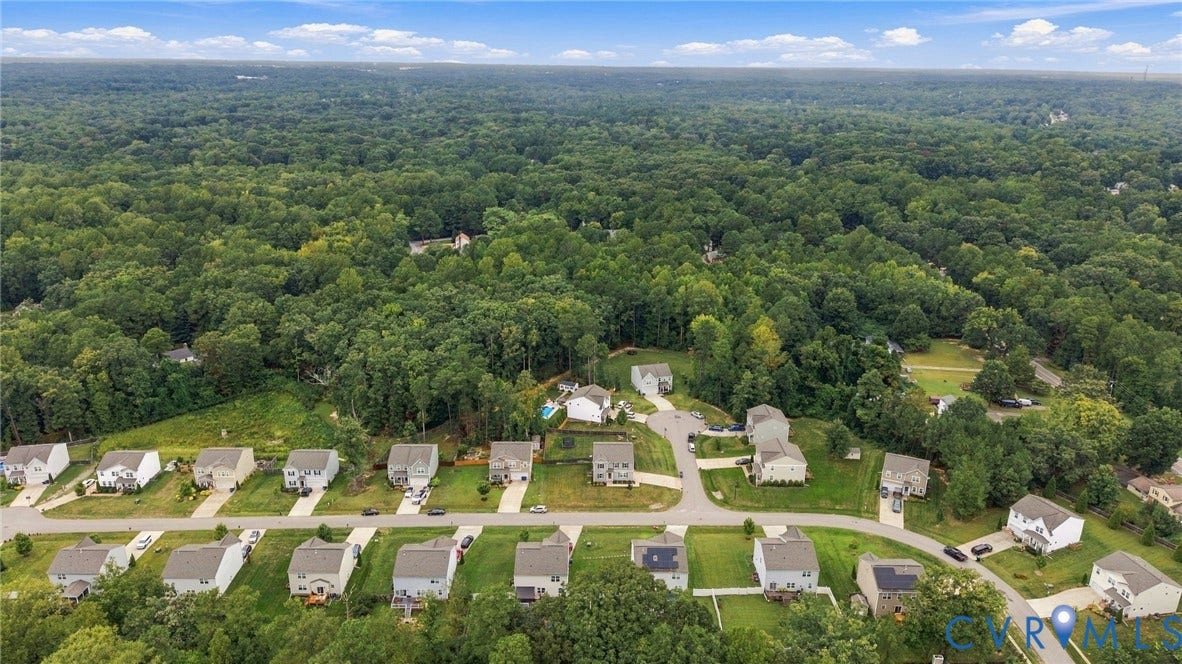 Sweeping aerial view highlights the neighborhoods peaceful setting surrounded by abundant mature greenery.