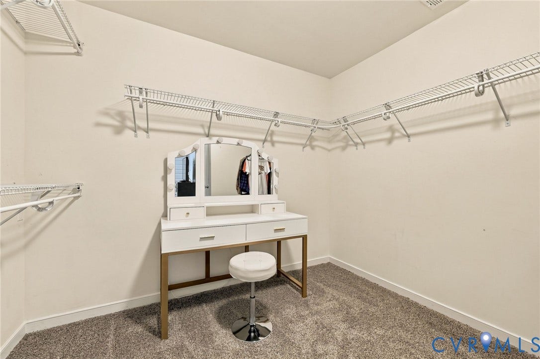 Large primary walk-in closet with ample shelving and hanging space.