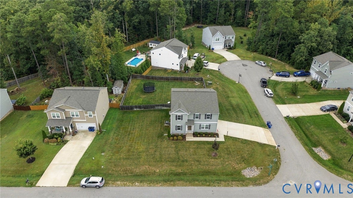 Aerial view showcases the homes setting within a quiet residential cul-de-sac surrounded by mature trees.