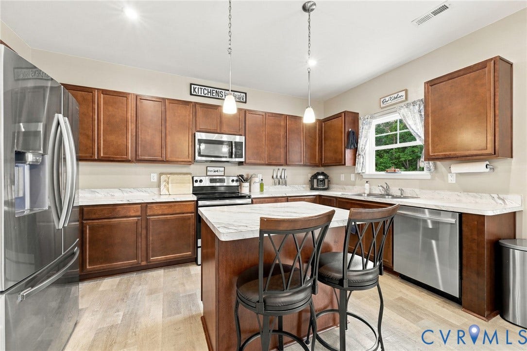 Spacious kitchen featuring abundant cabinetry, generous counter space, stainless steel appliances, and a center island with seating.