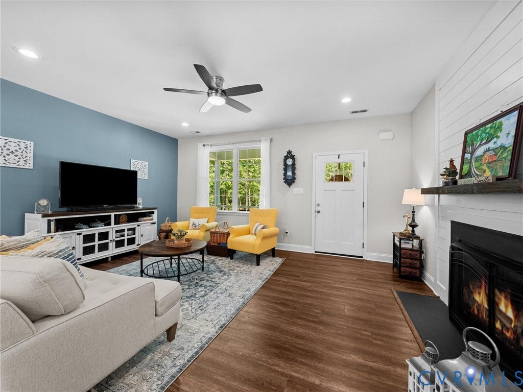 5927 Trenholm Village Drive, Trenholm Village, Powhatan, VA 23139 Expansive living area featuring wood-finish flooring, a ceiling fan with integrated lighting, a fireplace with a mantel, and a multi-pane window