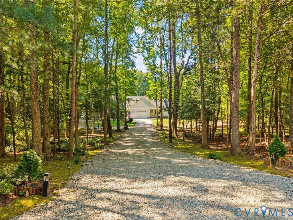 5927 Trenholm Village Drive, Trenholm Village, Powhatan, VA 23139 Gravel driveway leading to a single-story residence with a two-car garage, surrounded by mature trees
