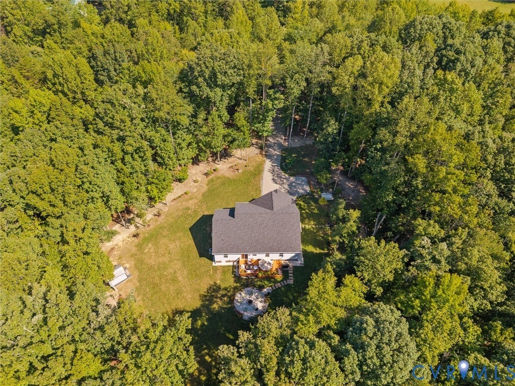 5927 Trenholm Village Drive, Trenholm Village, Powhatan, VA 23139 Expansive wooded surroundings with a gravel driveway, a large rear deck, a fire pit area, and a white shed