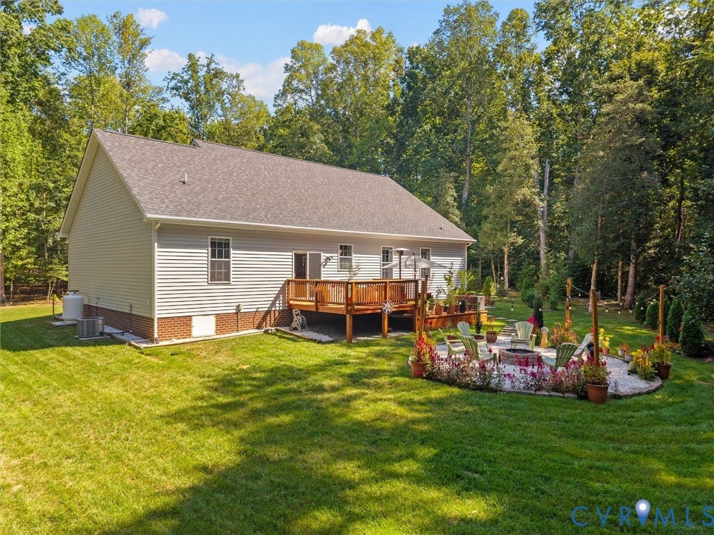 5927 Trenholm Village Drive, Trenholm Village, Powhatan, VA 23139 Expansive backyard featuring a manicured lawn, a multi-level wood deck, a stone fire pit area, and mature trees