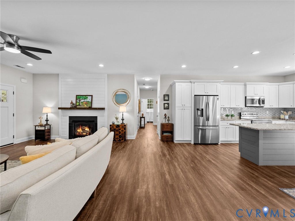 5927 Trenholm Village Drive, Trenholm Village, Powhatan, VA 23139 Open-concept living area featuring wood-finish flooring, a white-tiled fireplace, a ceiling fan, white cabinetry, and stainless steel appliances