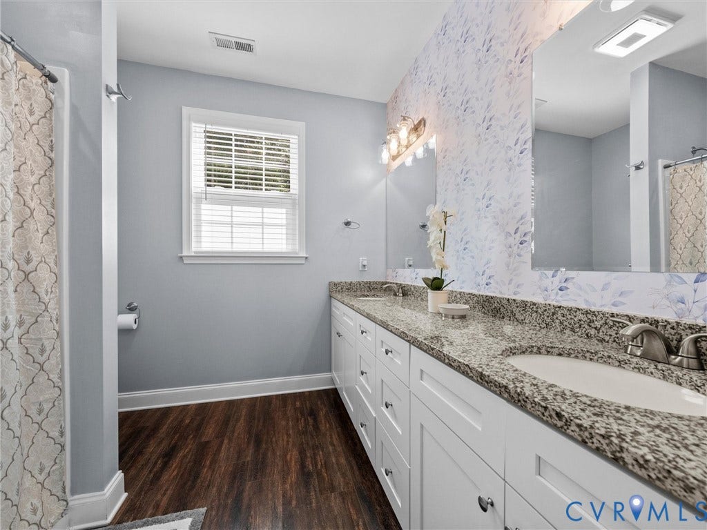 5927 Trenholm Village Drive, Trenholm Village, Powhatan, VA 23139 Double vanity with granite countertops, wood-finish flooring, two large mirrors, and a window with blinds