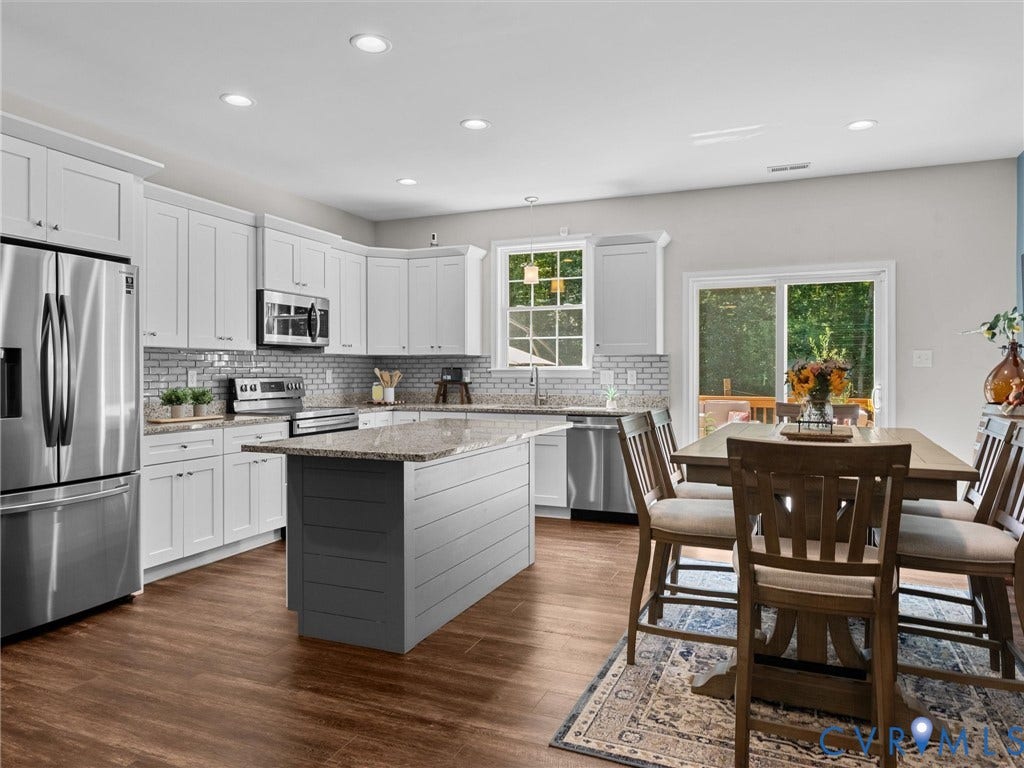 5927 Trenholm Village Drive, Trenholm Village, Powhatan, VA 23139 Kitchen featuring white cabinetry, stainless steel appliances, a center island with a stone countertop, wood-finish flooring, and a sliding glass door