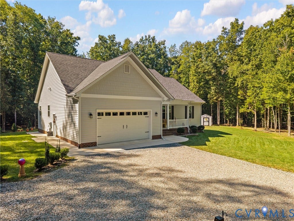 5927 Trenholm Village Drive, Trenholm Village, Powhatan, VA 23139 Light-toned siding exterior with a dark shingle roof, attached two-car garage, covered porch, and gravel driveway