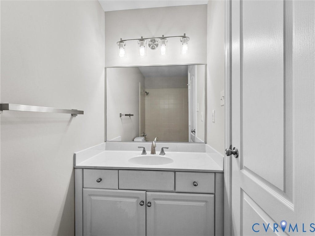 3700 Bremerton Drive, Wellesley, Henrico, VA 23233 White vanity with a single basin sink, brushed nickel faucet, and a large wall-mounted mirror
