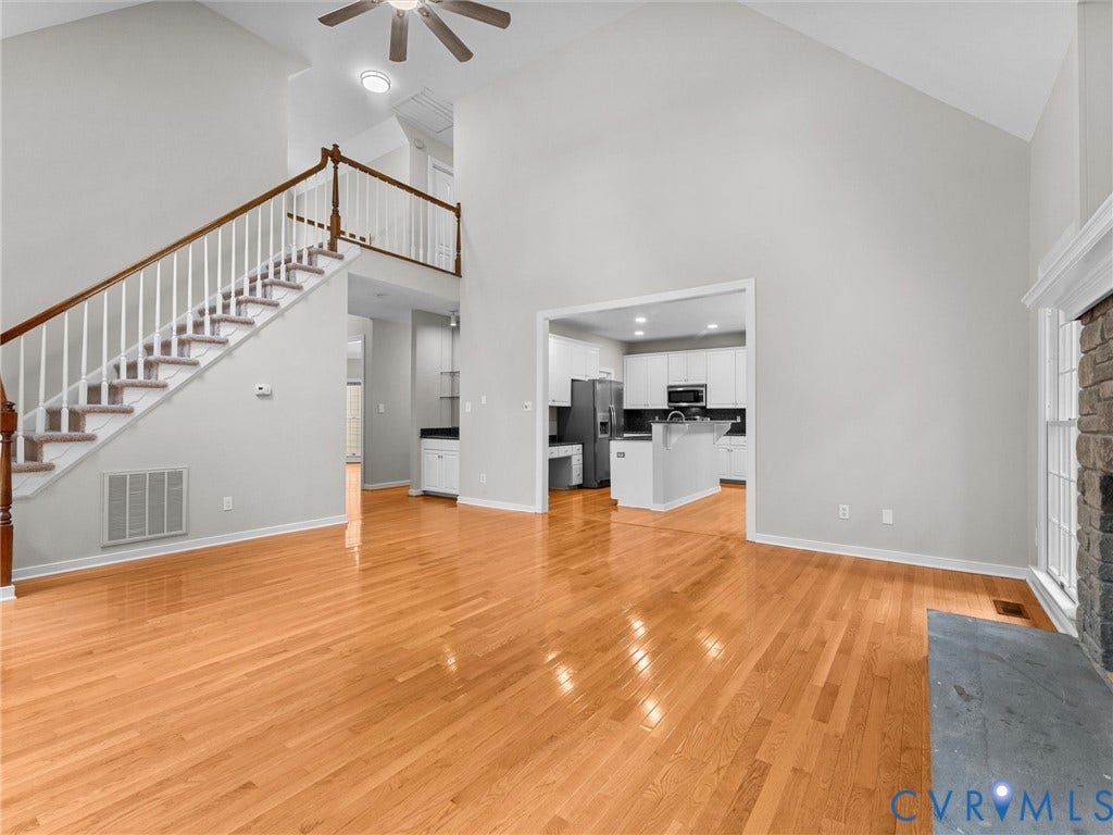 3700 Bremerton Drive, Wellesley, Henrico, VA 23233 Soaring vaulted ceiling with a ceiling fan, hardwood flooring throughout, stone-front fireplace with hearth, and an open-concept kitchen with white cabinetry and an island