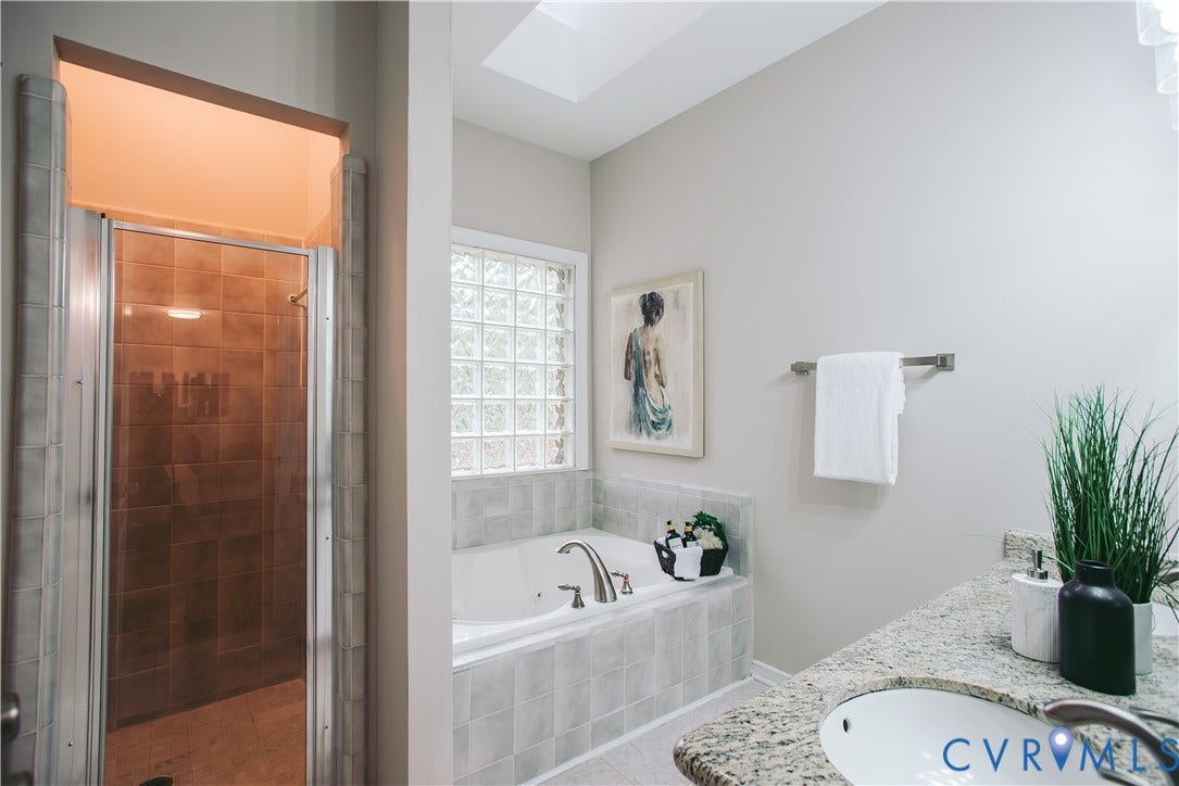 3700 Bremerton Drive, Wellesley, Henrico, VA 23233 Skylight, glass block window, separate shower with tiled walls, built-in soaking tub, and vanity with an integrated sink and stone countertop