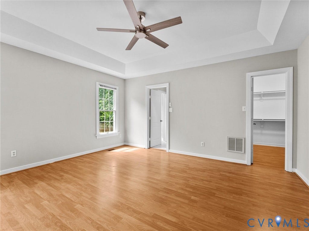 3700 Bremerton Drive, Wellesley, Henrico, VA 23233 Tray ceiling with a ceiling fan, wood-finish flooring, and a walk-in closet with built-in shelving