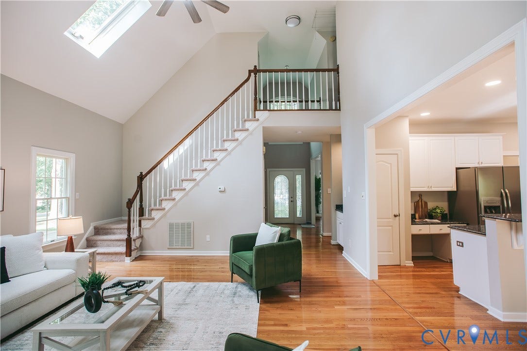 3700 Bremerton Drive, Wellesley, Henrico, VA 23233 Vaulted ceiling with skylight, wood-finish flooring, two-story staircase with wood handrail, upper-level balcony, and kitchen with white cabinetry and stainless-steel appliances