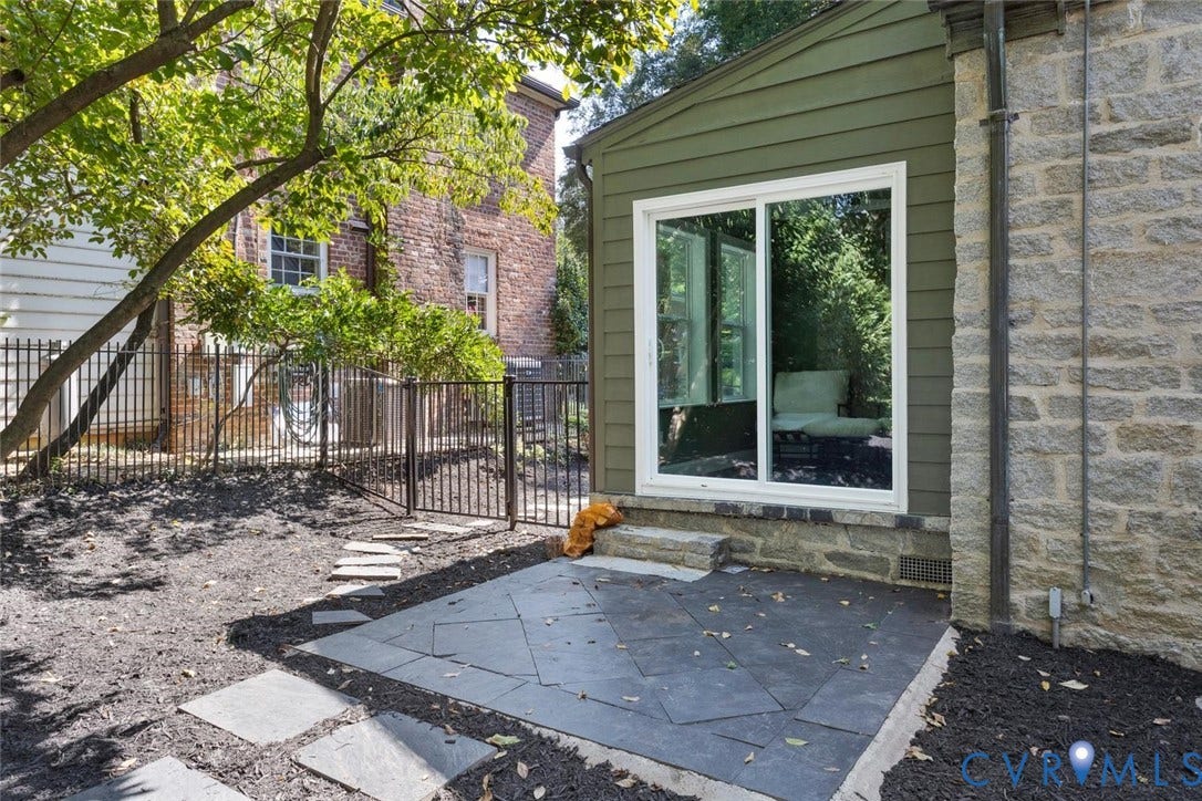 5113 King William Road, Westover Hills, Richmond, VA 23225 Stone patio with irregular-shaped pavers, featuring a white-framed sliding glass door and stone foundation