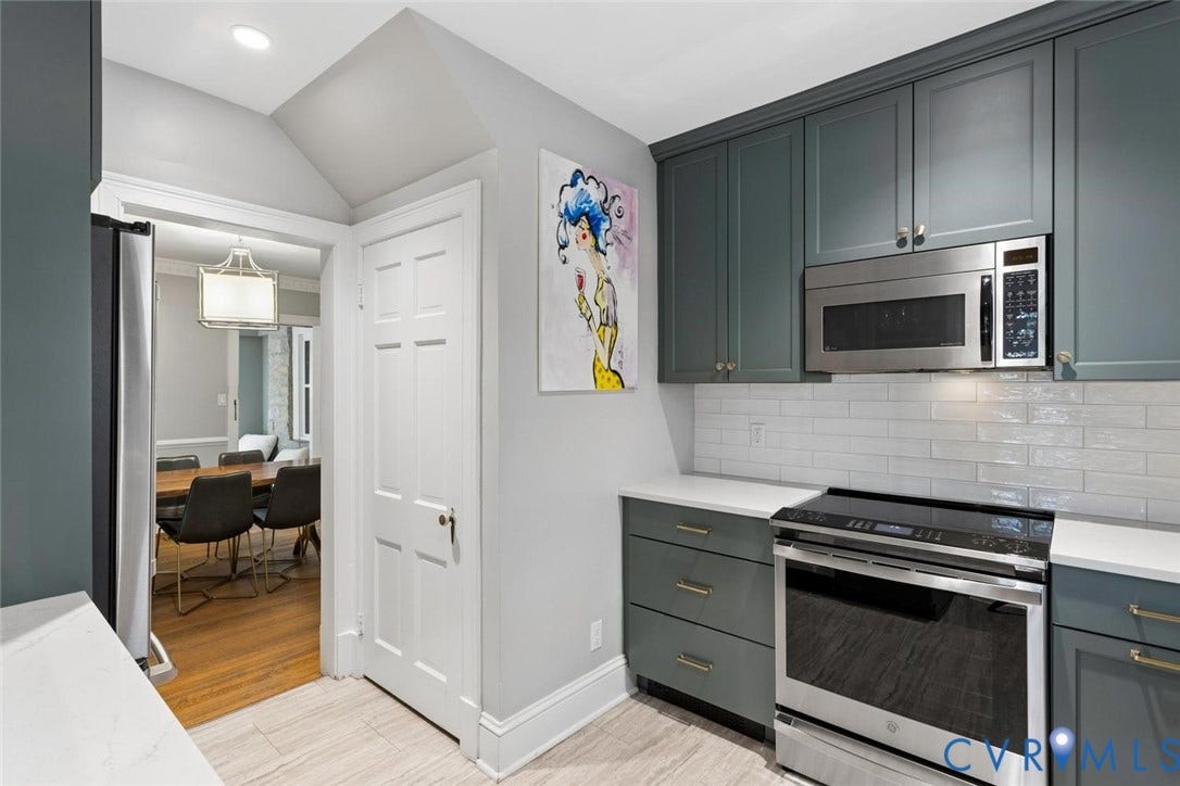 5113 King William Road, Westover Hills, Richmond, VA 23225 Modern kitchen featuring integrated stainless steel appliances, white subway tile backsplash, light-toned countertops, and deep-toned cabinetry with gold-finish hardware