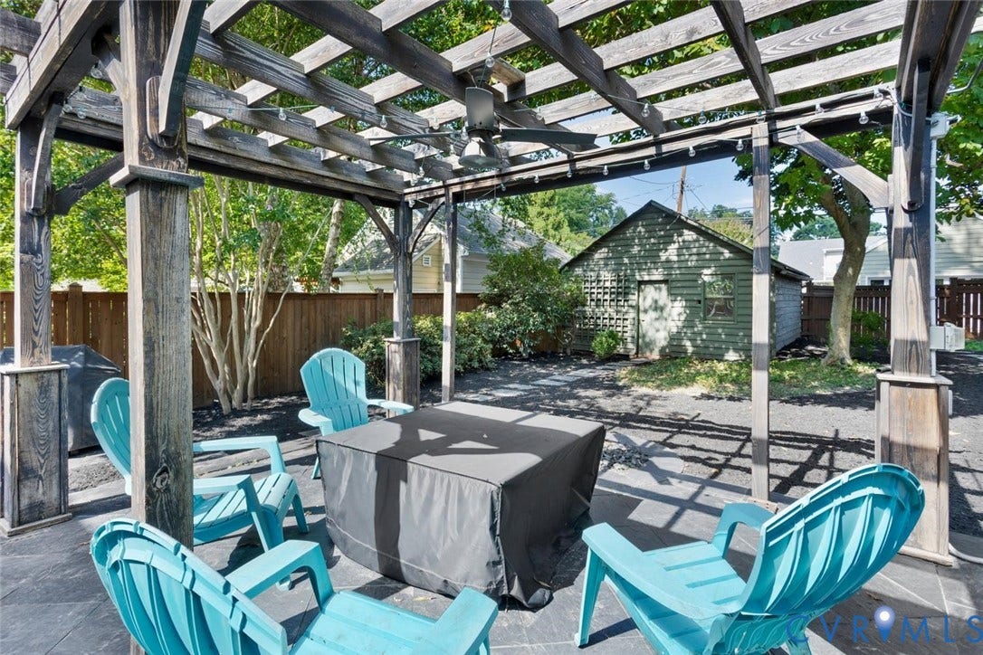 5113 King William Road, Westover Hills, Richmond, VA 23225 Sophisticated outdoor entertaining space featuring a slatted pergola with integrated overhead structure, concrete patio flooring, and multiple Adirondack-style seating arranged around a fire table with dark fabric cover