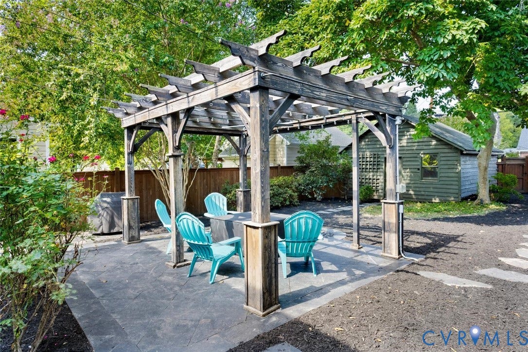 5113 King William Road, Westover Hills, Richmond, VA 23225 Wood pergola on a dark paver patio with a built-in outdoor speaker system, surrounded by mature trees and shrubs