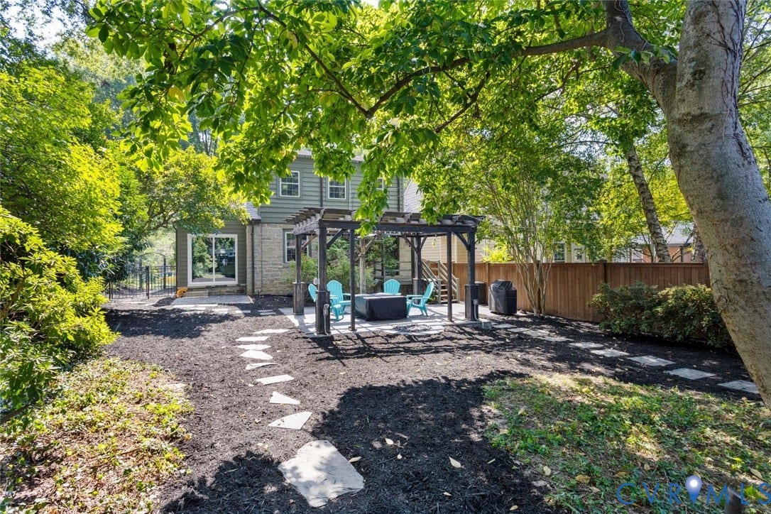 5113 King William Road, Westover Hills, Richmond, VA 23225 Expansive backyard featuring a stone patio, a wooden pergola structure, a privacy fence, and a stone paver pathway
