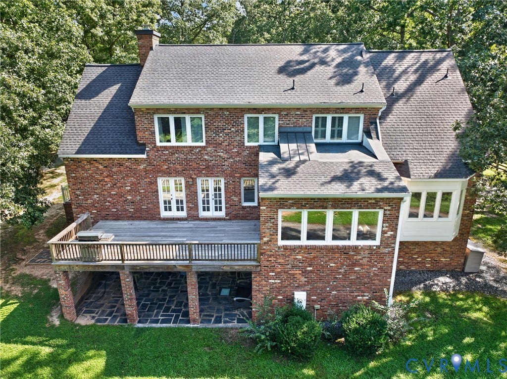 1108 Shallow Well Road, Manakin Sabot, VA 23103 Brick exterior with multiple windows, featuring a multi-level roofline, a raised wood deck, and a lower-level stone patio