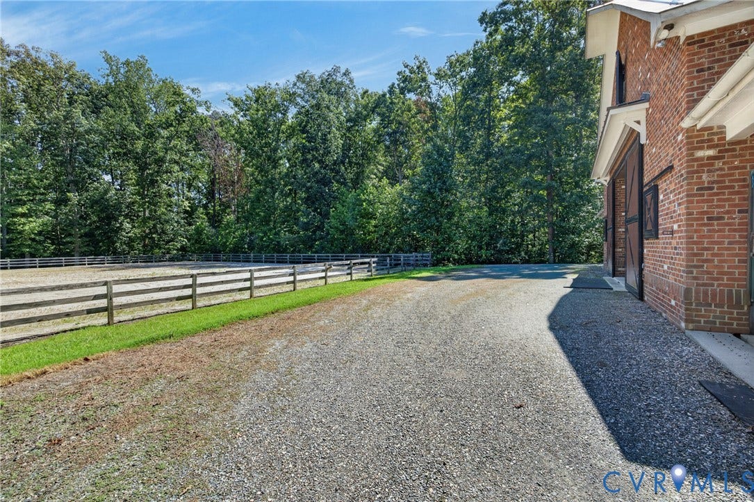 1108 Shallow Well Road, Manakin Sabot, VA 23103 Gravel driveway leading to a brick-clad building with sliding barn doors and a fenced outdoor arena