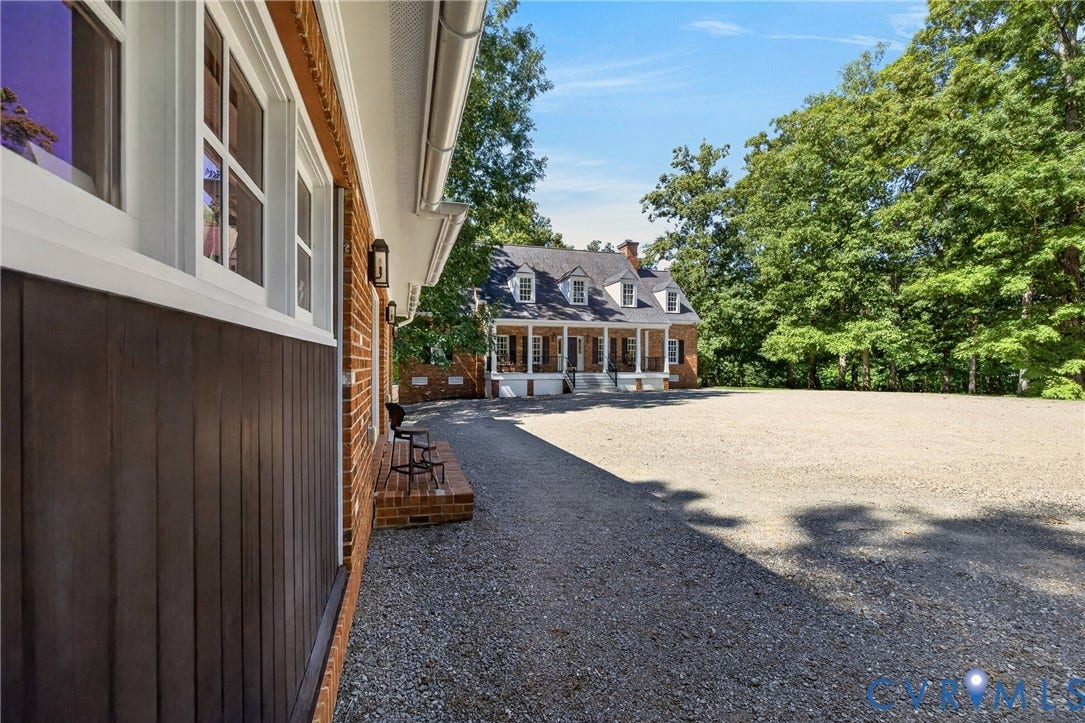 1108 Shallow Well Road, Manakin Sabot, VA 23103 Expansive gravel driveway with a brick facade structure featuring white-framed windows and dark vertical siding