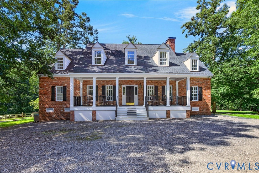 1108 Shallow Well Road, Manakin Sabot, VA 23103 Brick exterior featuring a covered porch with white columns, multiple dormer windows, a central entryway, and black window shutters