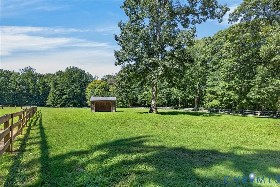 1108 Shallow Well Road, Manakin Sabot, VA 23103 Expansive grass field featuring wood fencing, a small open-front shed, and mature trees