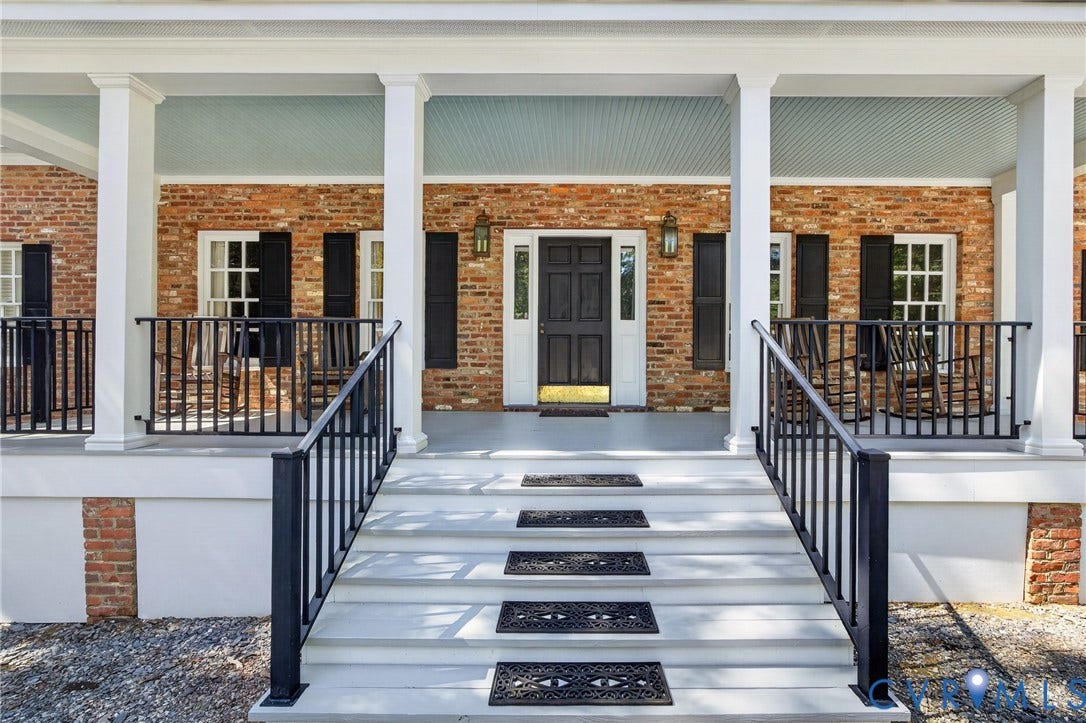 1108 Shallow Well Road, Manakin Sabot, VA 23103 Brick exterior with a covered porch, white columns, black metal railings, and a dark paneled entry door