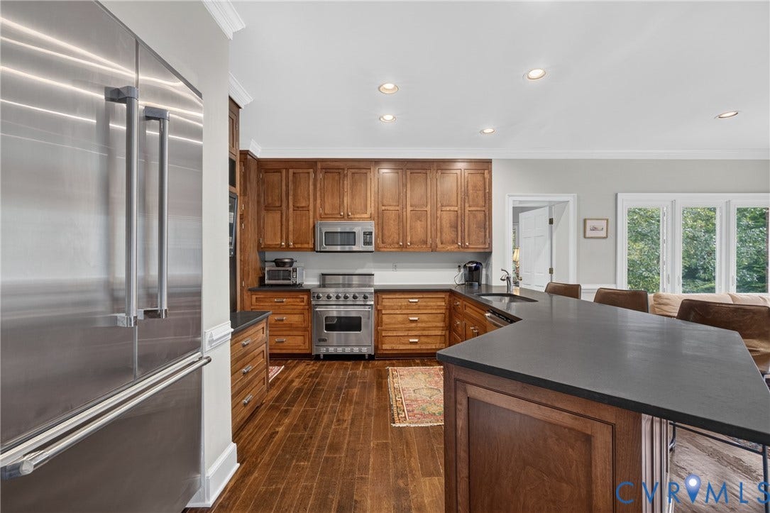 1108 Shallow Well Road, Manakin Sabot, VA 23103 Gourmet kitchen featuring stainless steel appliances, rich wood-finish cabinetry, dark stone countertops, wood-finish flooring, and recessed lighting
