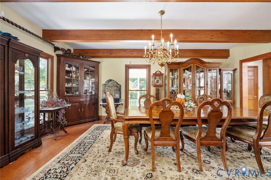 Hardwood flooring, exposed wood beam ceiling, brass chandelier, and wood-frame windows with natural light