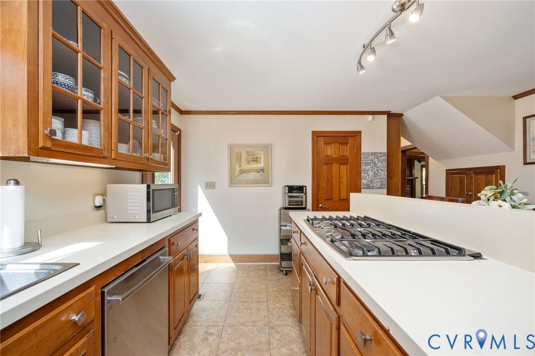Kitchen featuring wood cabinetry, solid surface countertops, a built-in gas cooktop, and a stainless steel dishwasher
